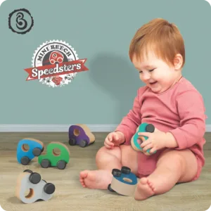 A toddler is sitting on the floor playing with wooden toy cars.