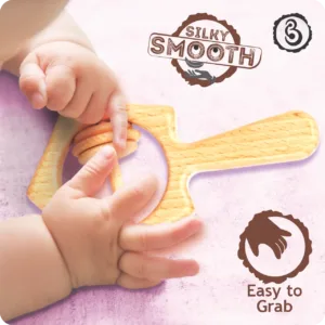 Baby’s hands grasping the silky smooth handle of a wooden star rattle.