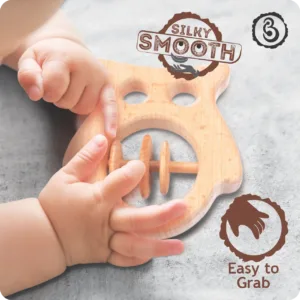 Baby hands grasping a silky smooth wooden owl rattle.