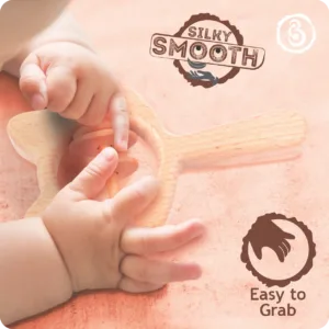 Close-up of a baby's hands grasping the silky smooth wooden cat rattle.