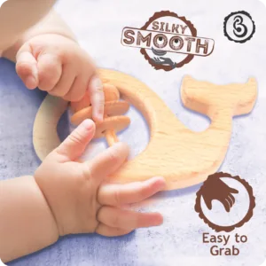 Baby's hands playing with a silky smooth, easy-to-grab wooden whale infant toy.