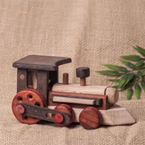 Wooden toy train engine on a textured burlap background with green leaves.