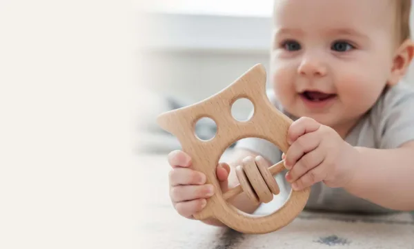 Baby holding wooden rattle toy